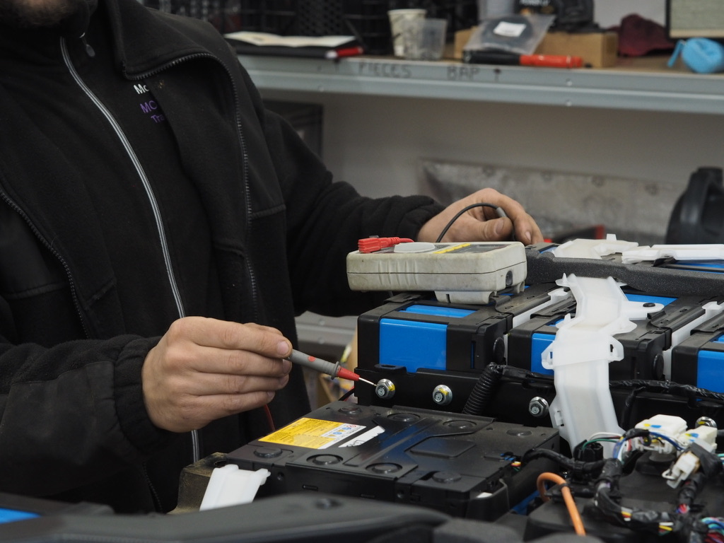 Pourquoi ma voiture électrique ne charge plus ? Diagnostic et solutions 2 Mécanicien utilisant un outil de diagnostic pour tester les cellules d'une batterie de véhicule électrique.