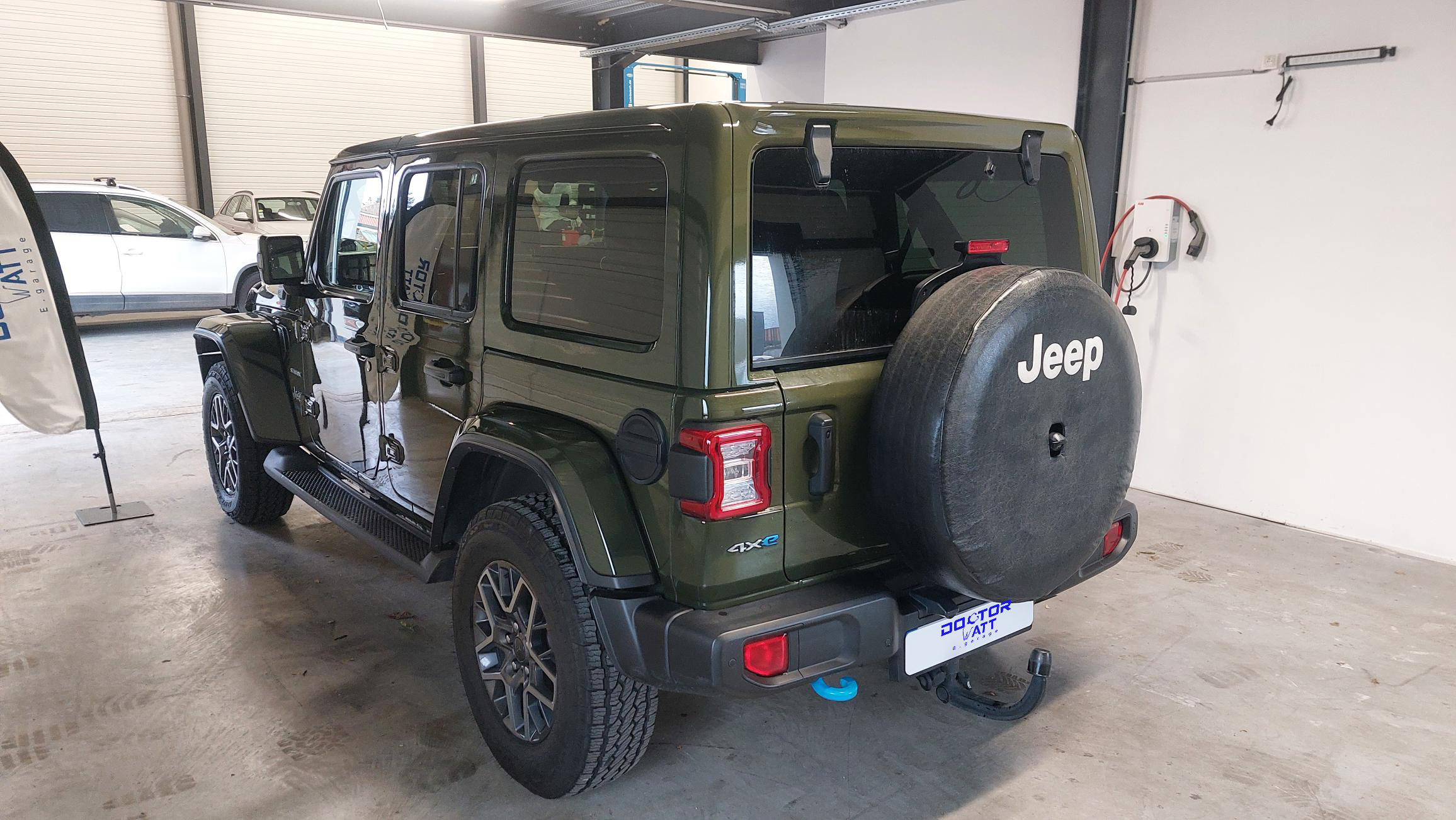 Vue arrière d'une Jeep Wrangler Unlimited Sahara hybride en excellent état, avec le pneu de secours et les feux arrière.