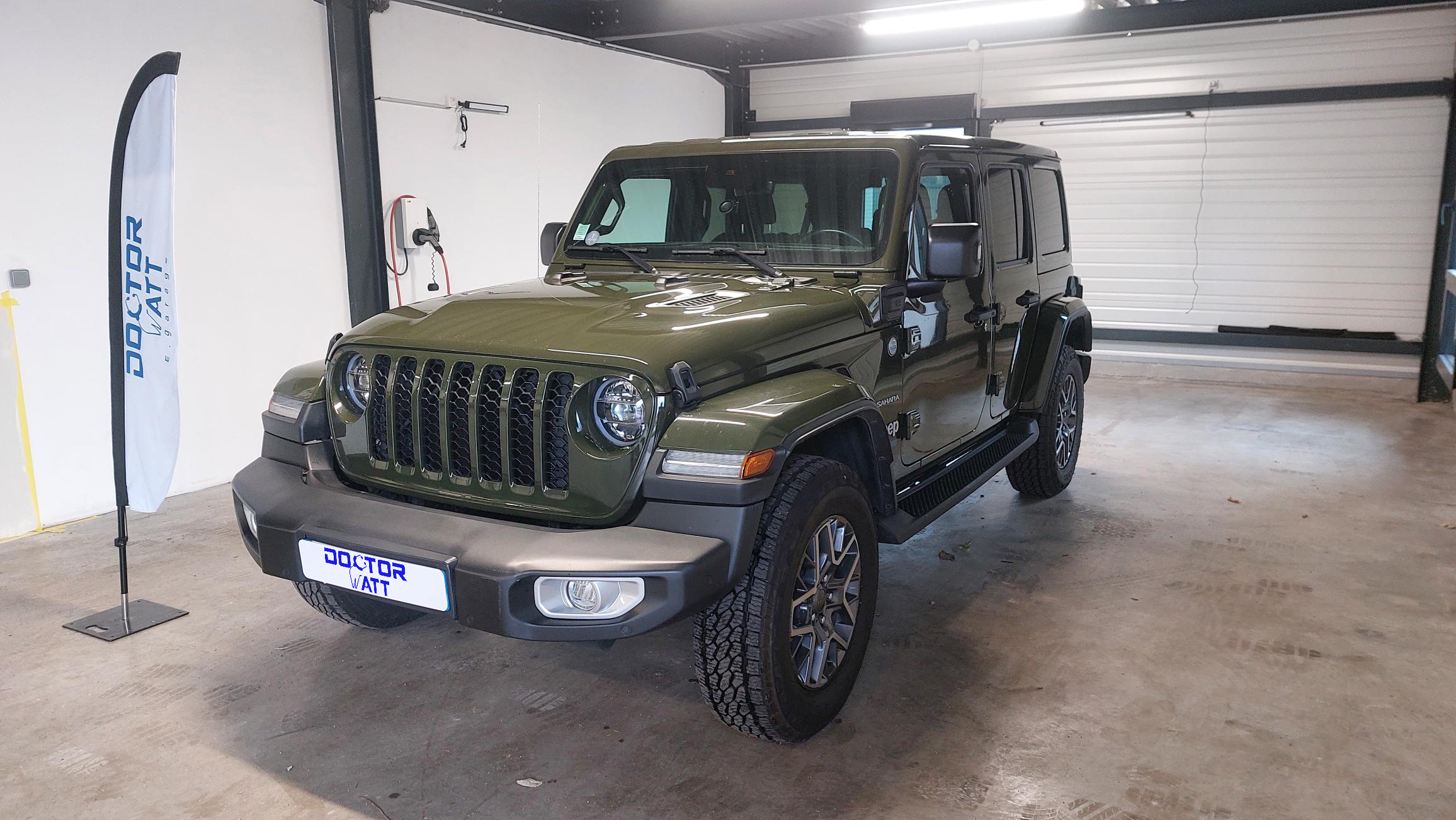 Vue latérale d'une Jeep Wrangler Unlimited Sahara hybride en excellent état, mettant en valeur ses lignes élégantes, ses portes et ses roues.